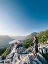 Lovcen, Montenegro - 10.08.21: Girl-photographer photographs bride and groom sitting on a rock in the mountains above