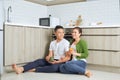 Love is in the air. Beautiful young couple drinking coffee and orange juice while sitting on the kitchen floor at home Royalty Free Stock Photo