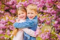 Love is in the air. Kids in love pink cherry blossom. Romantic babies. Couple kids walk sakura tree garden. Tender love