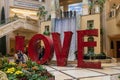 The Love Art Sculpture in the waterfall atrium at The Venetian Resort and Hotel with lush green trees and plants, colorful flowers Royalty Free Stock Photo