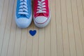 Love background with two different sneakers and blue heart