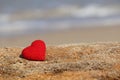 Love on the beach, red knitted heart on blue sea background