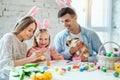 We love beautiful traditions.Mom and daughter paint eggs, dad holds a home decorative rabbit