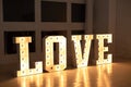 Love big white letters with led retro bulbs glowing. Word LOVE with a big letters. Inscription is love. Glowing large letters.