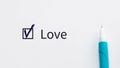 Love - checkbox with a tick on white paper with blue pen. Checklist concept.