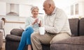 Love, coffee and elderly couple relax on a sofa, happy and laughing, talking and bonding in their home. Tea, chill and Royalty Free Stock Photo
