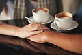 Love, coffee shop and couple holding hands, relax and romantic support on morning date for latte, espresso or beverage