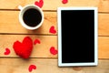 Love composition - coffee cup, tablet and craft heart on wooden background.