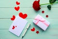 Love composition - red rose, gift box and greeting card on blue wooden background.