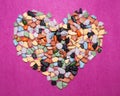 Love concept.Heart-shaped decoration from colorful pebbles on a pink background.choco rocks looks like pebbles Royalty Free Stock Photo