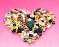 Love concept.Heart-shaped decoration from colorful pebbles on a pink background.choco rocks looks like pebbles Royalty Free Stock Photo