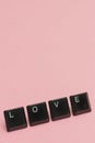 Love concept with keyboard letters on pink background.  Vertical view Royalty Free Stock Photo