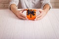 Love concept. Man holding orange gift with black ribbon in hands. Women`s day. St. Valenine`s day