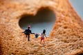 Love Concept. Miniature of Happy Family Walking on Burned Sliced Toasted Bread with a Heart shape Royalty Free Stock Photo