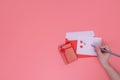 Love concept, a right-hand holds a pen write on a white paper. that put on a red envelope and red gift box beside Royalty Free Stock Photo