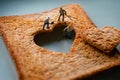 Love Concept. Sad Relationship. Group of Worker Miniature Fixing a Burned Sliced Toasted Bread with a Heart shape