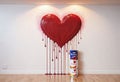 Love concept. Wooden ladder near white wall with big red painted heart