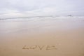 Love concept , written by hand in sand on a sea beach with soft wave. Royalty Free Stock Photo