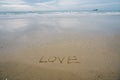 Love concept , written by hand in sand on a sea beach with soft wave. Royalty Free Stock Photo