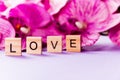 Love consisting of wooden cubes on a purple orchid background, Valentine`s Day. Selective Focus Royalty Free Stock Photo