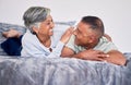 Love, conversation and mature couple on their bed while relaxing, bonding and spending time together. Happy, smile and Royalty Free Stock Photo