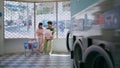 Love couple chatting laundry room. Teenage girl guy washing clothes in public Royalty Free Stock Photo