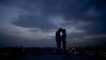 Love couple enjoying romantic moments on rooftop, illuminated city at night