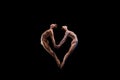 Love. Couple of graceful and flexible ballet dancers making heart shape of their bodies over black background