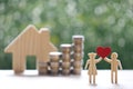 Love couple holding heart shape and stack of coins money with model house on natural green background, Saving for lover or family Royalty Free Stock Photo