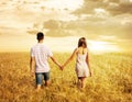 Love couple walking in sunset field holding hands Royalty Free Stock Photo