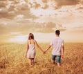 Love couple walking in sunset field holding hands Royalty Free Stock Photo