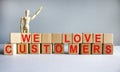 `We love customers` written on wood blocks. Business concept. Wooden model of human. Copy space