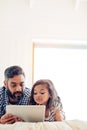 Love, digital tablet and father with daughter on a bed for reading, story and learning in their home together. Family Royalty Free Stock Photo