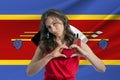 Love Esvatini A girl holds a heart on her chest in her hands against the background of the flag of Esvatini The concept Royalty Free Stock Photo