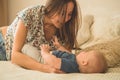 Love and family. Home portrait of a baby boy with mother on the bed. Mom play and kissing her child Royalty Free Stock Photo