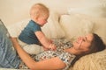 Love and family. Home portrait of a baby boy with mother on the bed. Mom play and kissing her child Royalty Free Stock Photo