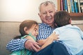 The love of a family, isnt it grand. Portrait of a happy brother and sister giving their grandfather a loving hug at Royalty Free Stock Photo