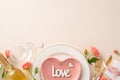Top view snapshot of intimate Valentine\'s dinner scene. Heart-shaped plate, cutlery, white wine adorn beige background