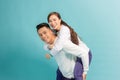 Love forever, fun together. Young handsome boyfriend is piggybacking his cute lover, on blue background Royalty Free Stock Photo