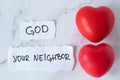 Love God and your neighbor, handwriting on paper with two red hearts on white marble table Royalty Free Stock Photo