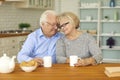 Happy senior couple drinking tea and hugging each other sitting at table in the kitchen Royalty Free Stock Photo