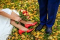 Love and happiness on wedding day. Close up of bride`s and groom`s feet and shoes, colorful bridal bouquet and autumn leaves Royalty Free Stock Photo