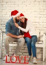 Love happy couple in Christmas hats on white wall Royalty Free Stock Photo