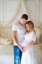 Love and happy pregnancy.Gentle beautiful pregnant couple near tulle curtains