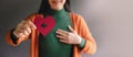 Love, Health Care, Donation and Charity Concept. Close up of Smiling Volunteer Woman Holding a Heart Shape with Cross Sign Paper.