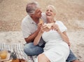 Love and healthy senior couple on picnic at a beach eating sandwich with funny conversation for wellness, healthcare or