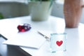 Love heart shape on a paper weight with pen and paper on a desk to write a valentines card or love letter