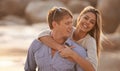 Love him more each day. A happy young couple enjoying a piggyback ride on the beach at sunset. Royalty Free Stock Photo