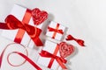 Love holiday background - white gift boxes with red bow, sweet lollipops hearts on white wood board as border, copy space. Royalty Free Stock Photo