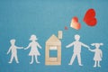 Love in home and family concept. Paper family holding hands and wooden house with red hearts from chimney pipe on blue background Royalty Free Stock Photo